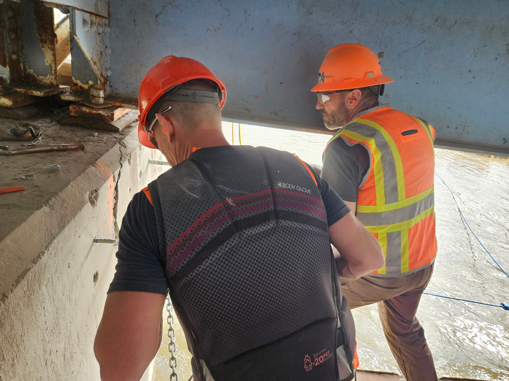 Lenci Kappes (right) running a hammer drill next to Ryan Dahlke (left) on Friday.