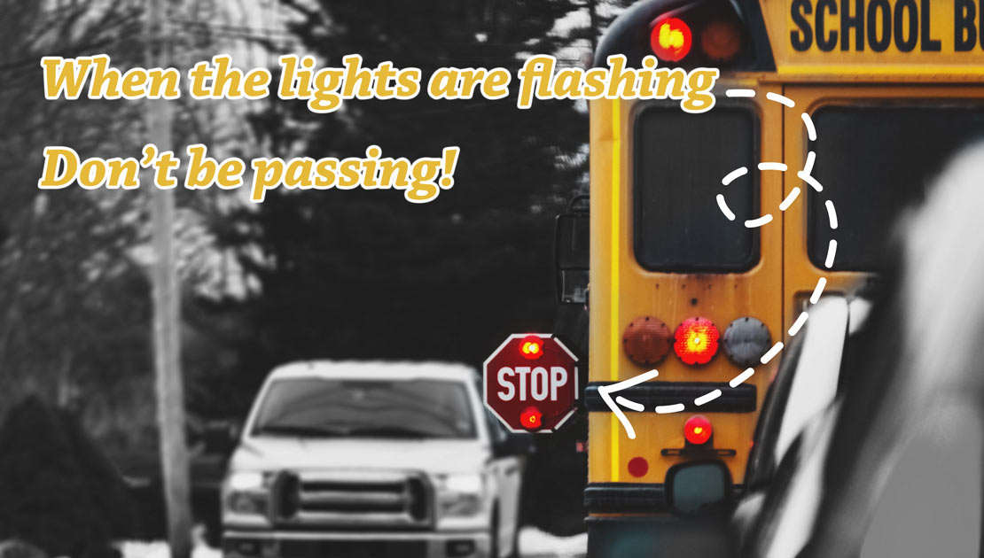The back of a school bus with the STOP sign extended and text saying When the lights are flashing, don't be passing!