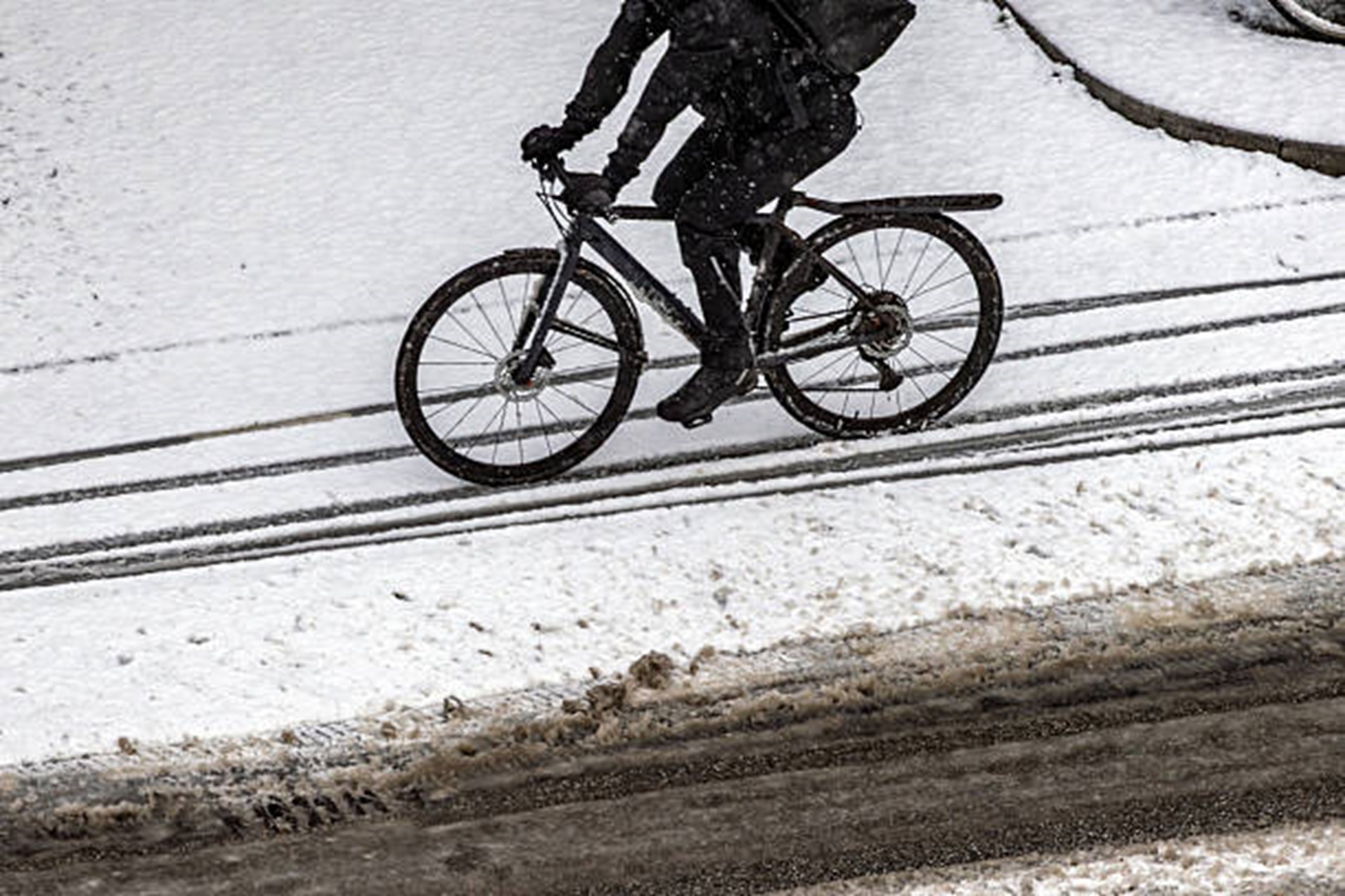 Bicyclist riding over slushy winter street