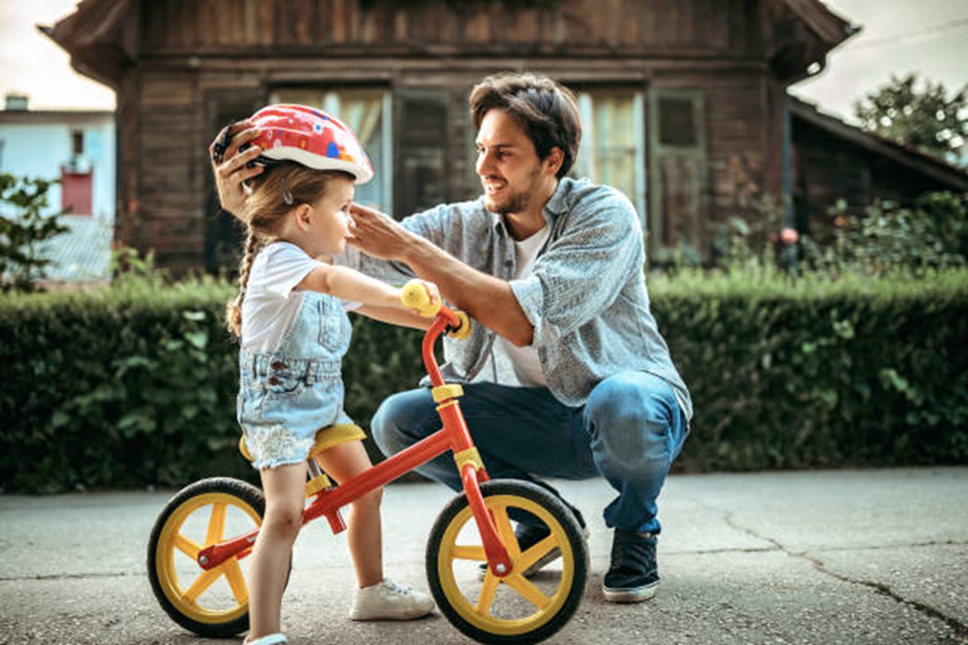 Man helping a small girl fit her bicycle helmet