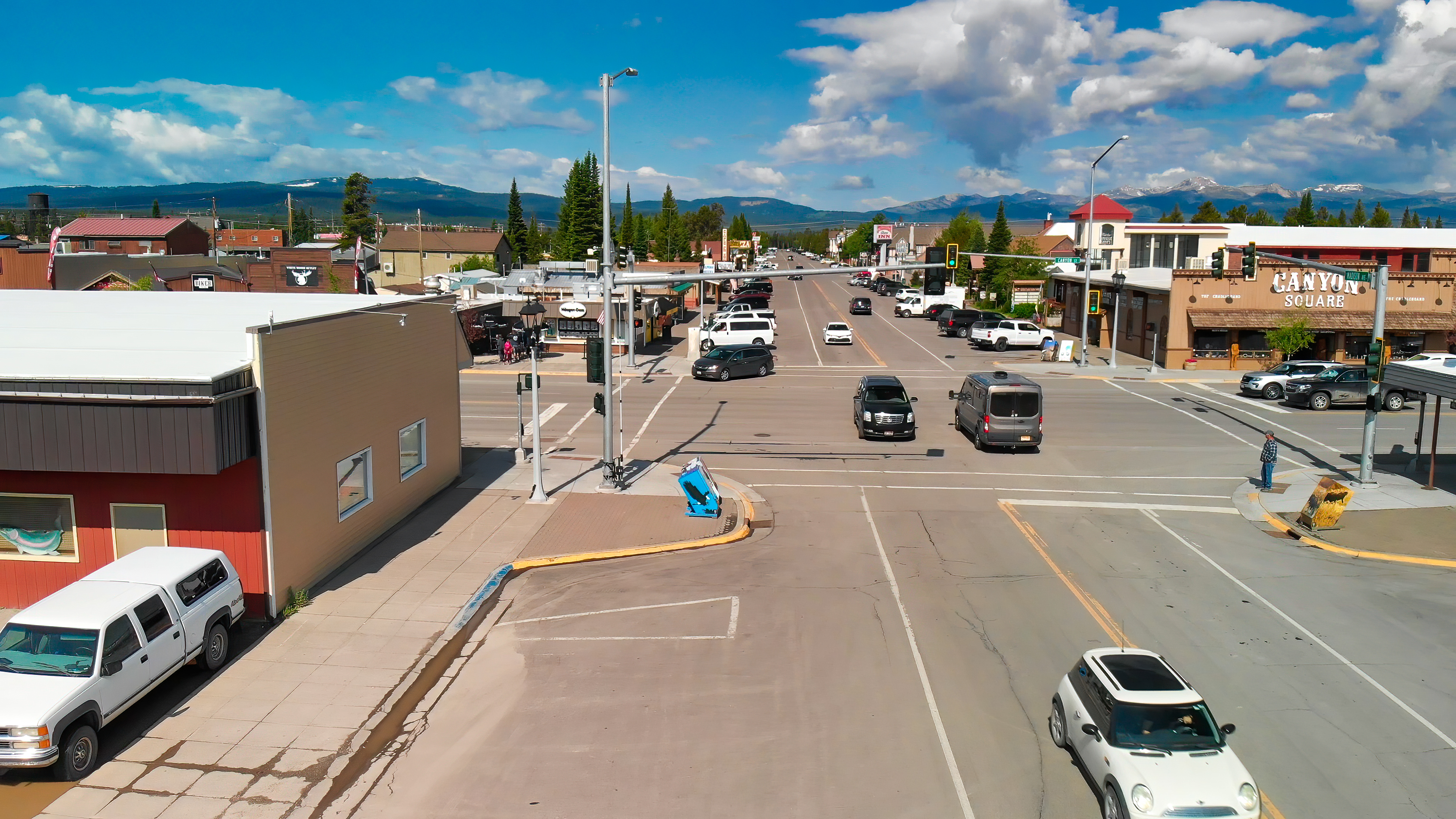 Busy intersection in downtown Butte where a pedestrian waits to cross the road, and cars are driving through